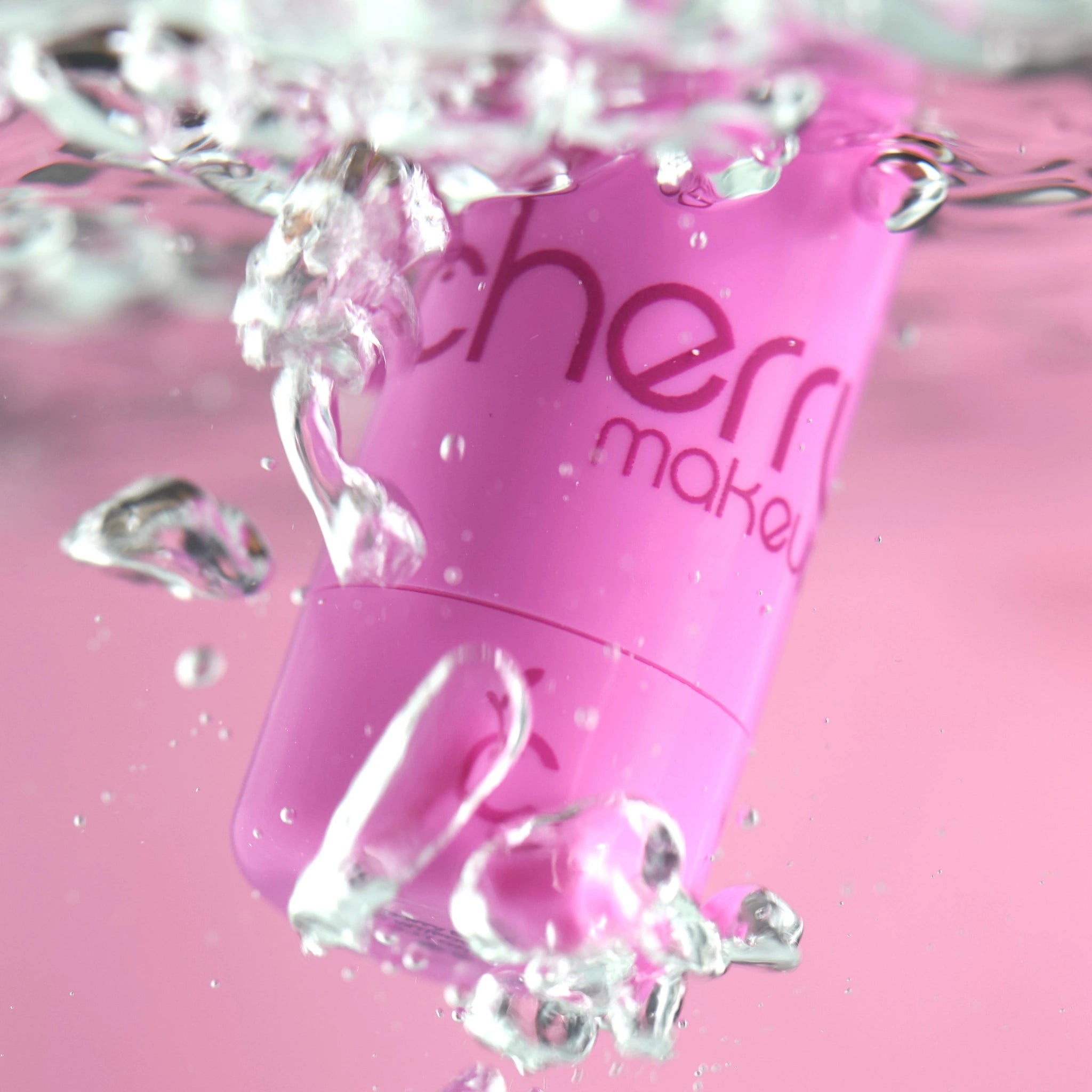 Pink makeup product with water droplets on a pink background