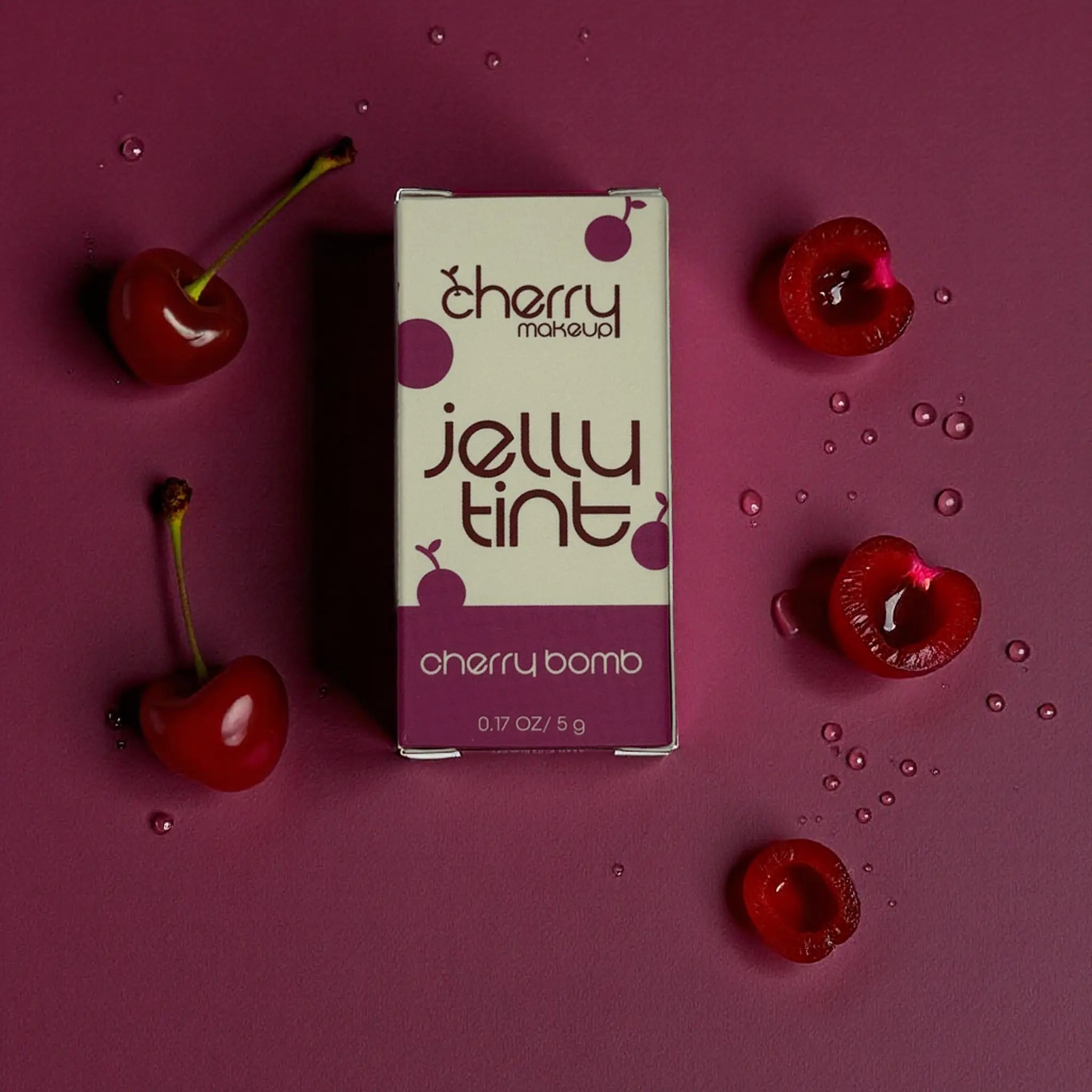 Cherry-themed jelly tint packaging surrounded by cherries on a purple background