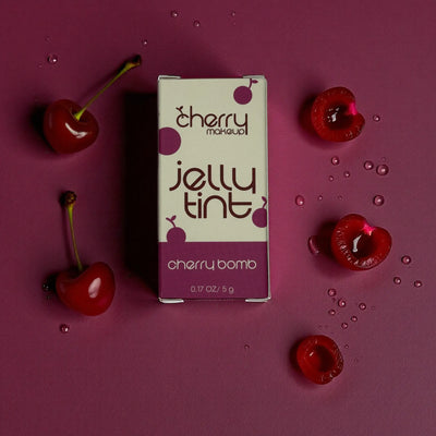 Cherry-themed jelly tint packaging surrounded by cherries on a purple background