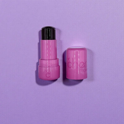 Pink lip balm with black cap on a purple background
